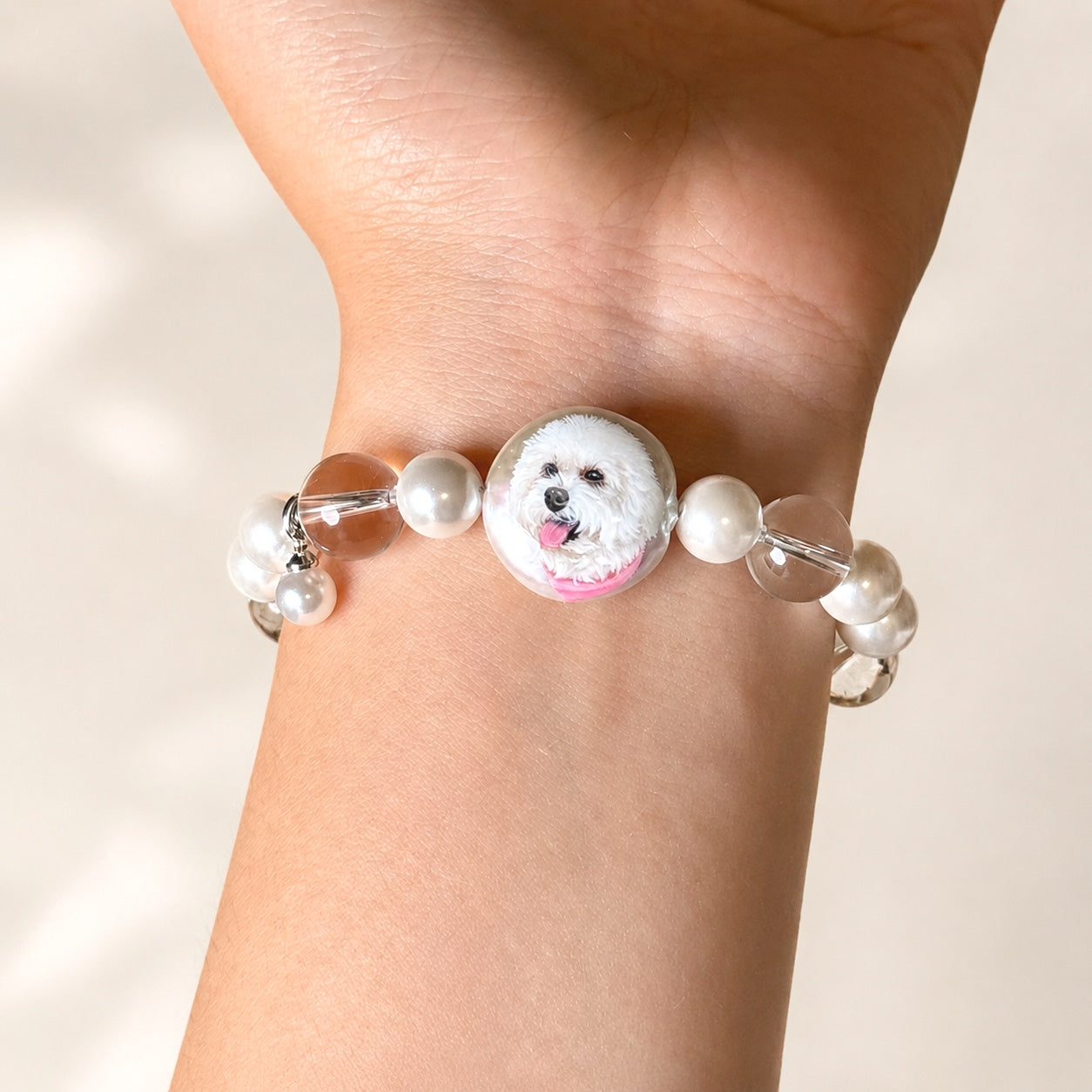 Custom pet face bracelet worn on a wrist with two white dog portrait charms facing outward.