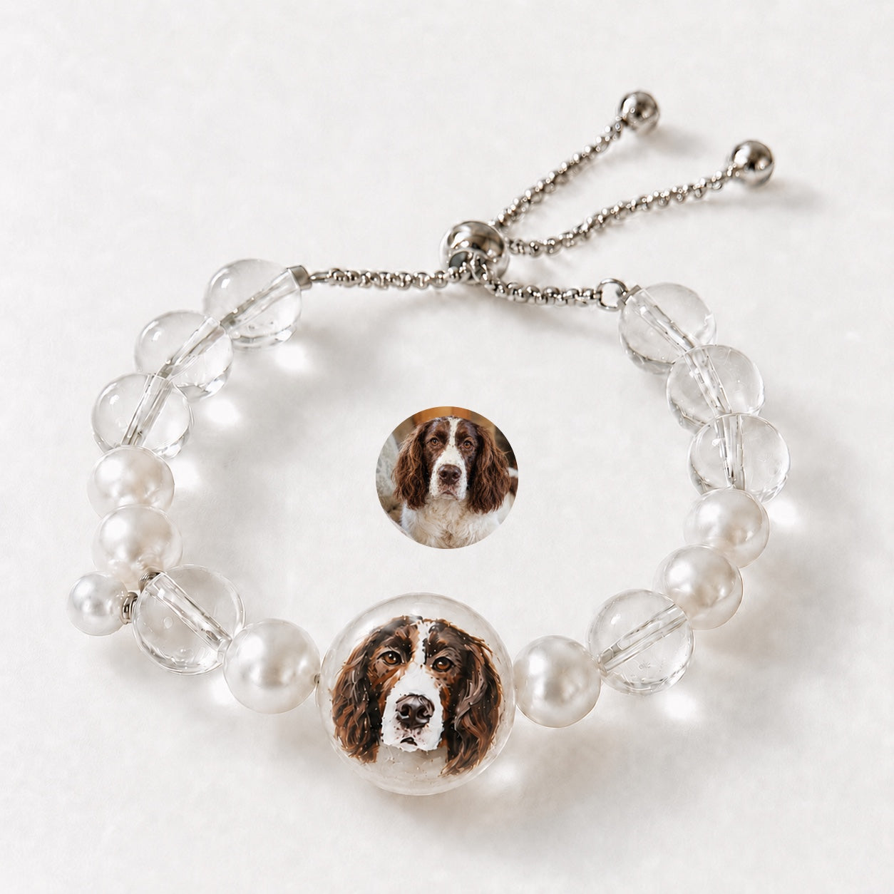 Custom pet face bracelet with two brown and white dog portrait charms and adjustable chain.