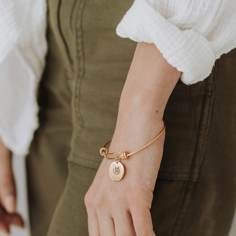 Engraved pet portrait bangle shown as a delicate adjustable bracelet worn with a casual outfit.
