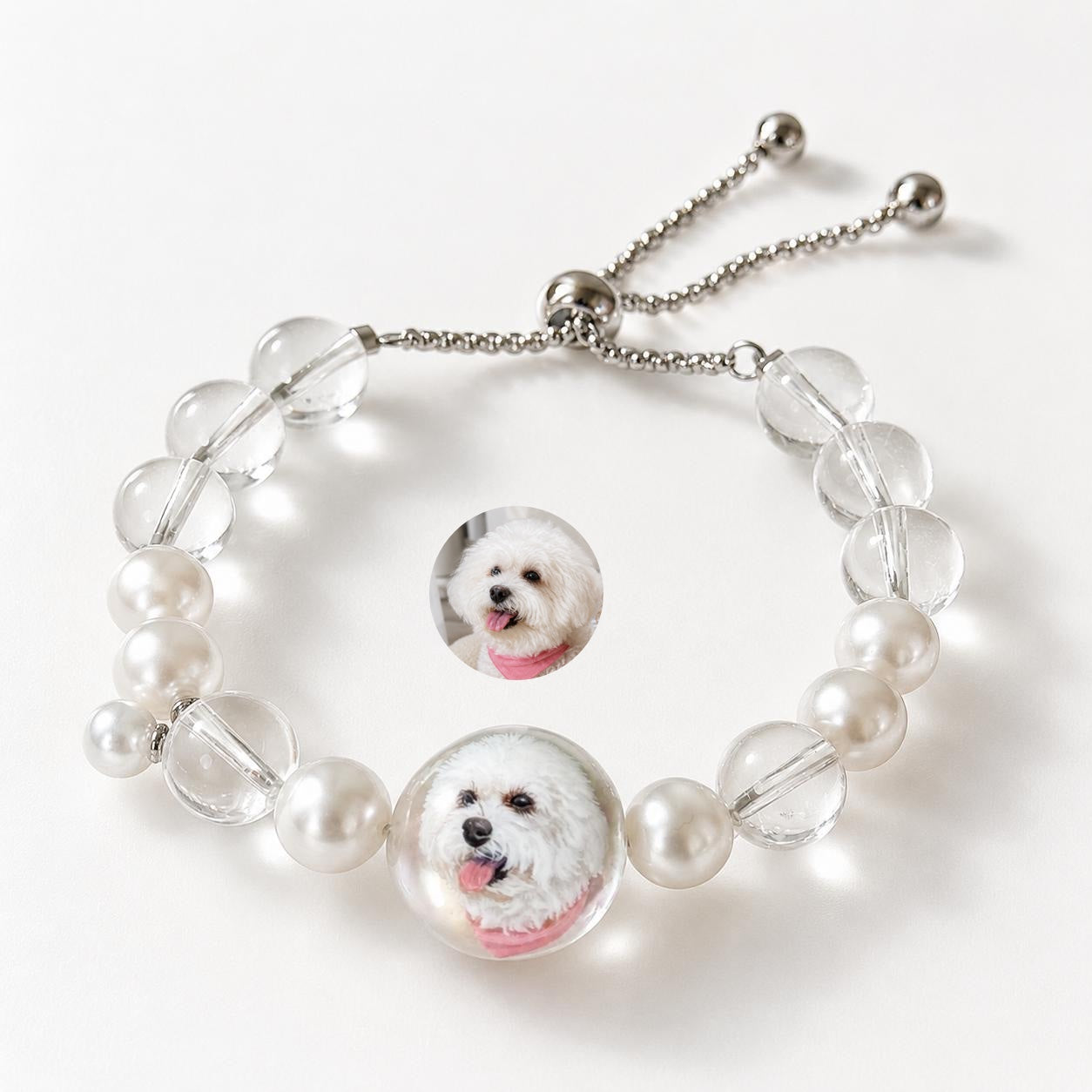 Custom pet face bracelet with two white dog portrait charms, pearls, crystals, and adjustable chain.