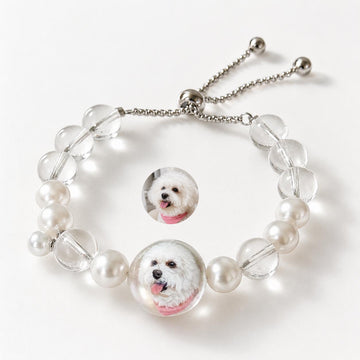 Custom pet face bracelet with two white dog portrait charms, pearls, crystals, and adjustable chain.