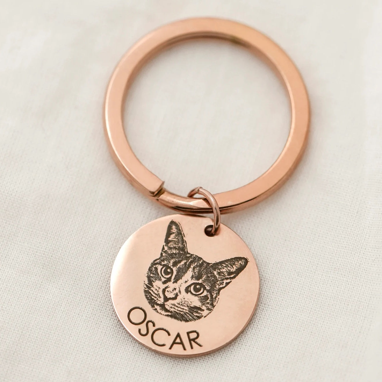 Engraved pet photo keychain in rose-gold-tone steel with a cat portrait and the name Oscar.