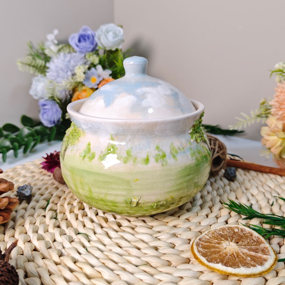 Back view of a handcrafted ceramic pet urn with a beach-inspired glaze, fitted lid, and textured wave details.