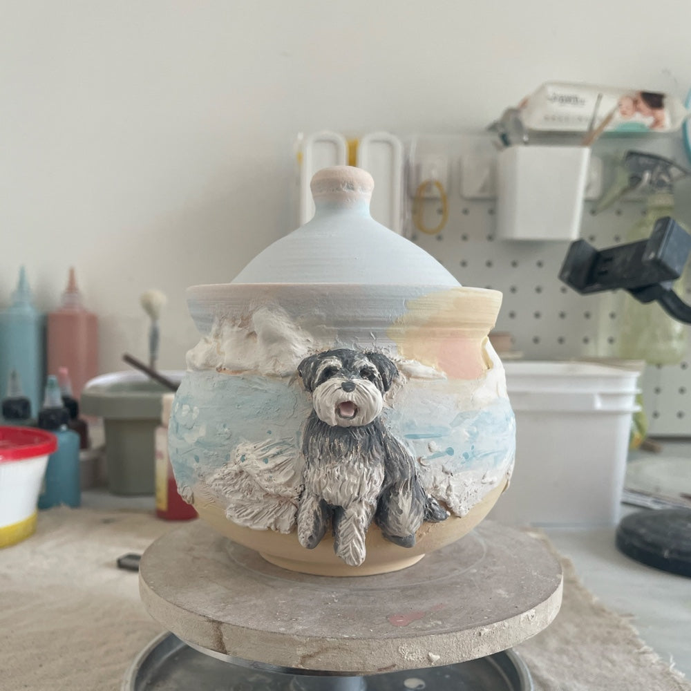 Styled front view of a custom ceramic pet urn with a gray dog sculpture and painted tree landscape.