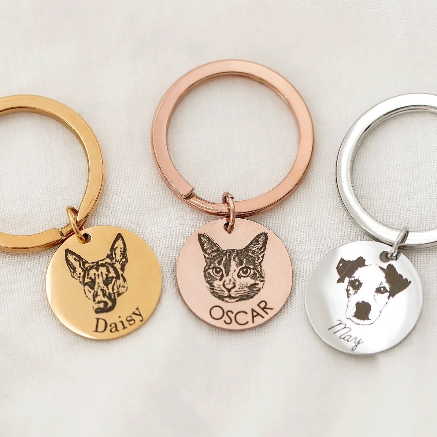 Engraved pet photo keychain collection of gold, rose-gold, and silver pet portrait key rings.
