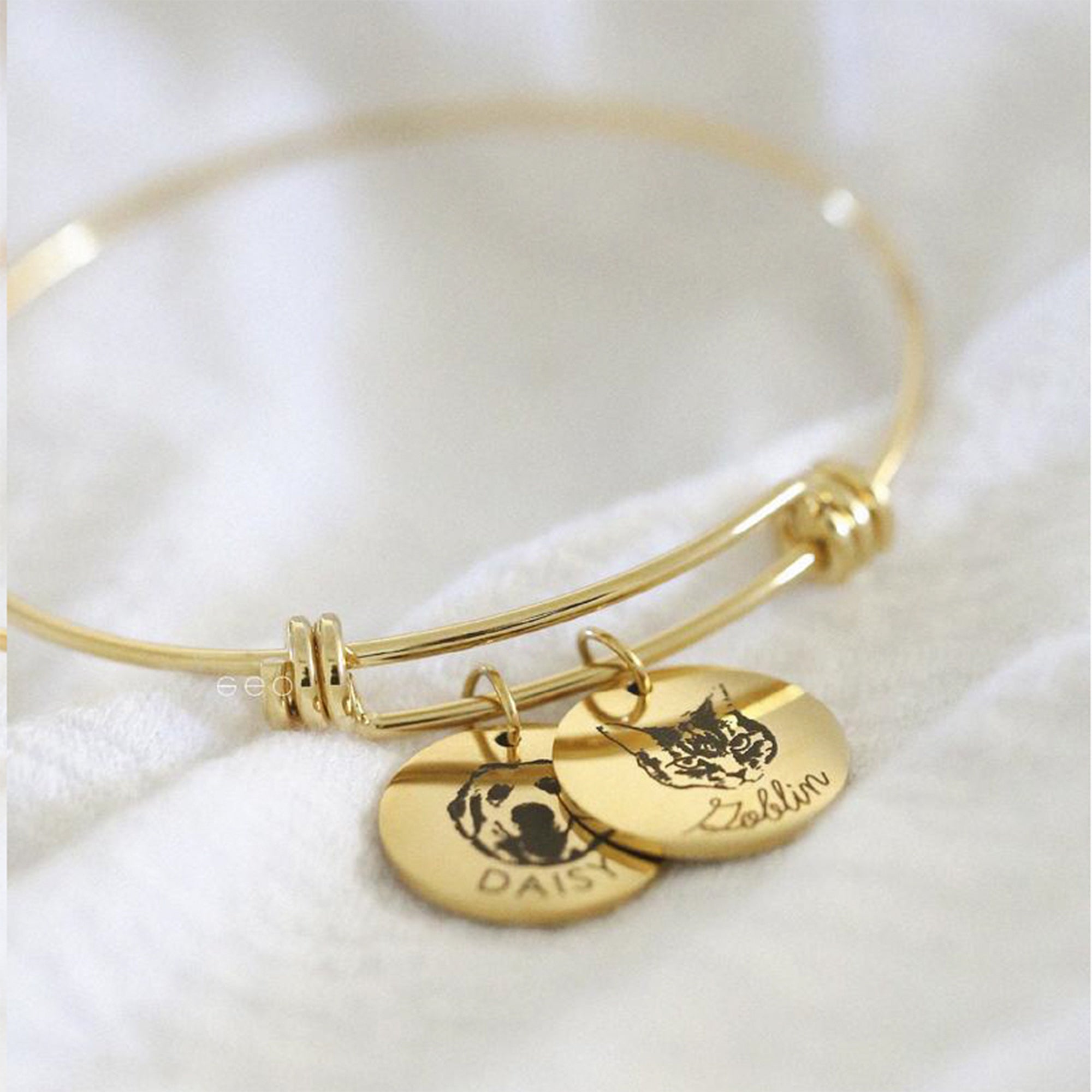 Engraved pet portrait bangle with two engraved pet portrait charms and personalized names.