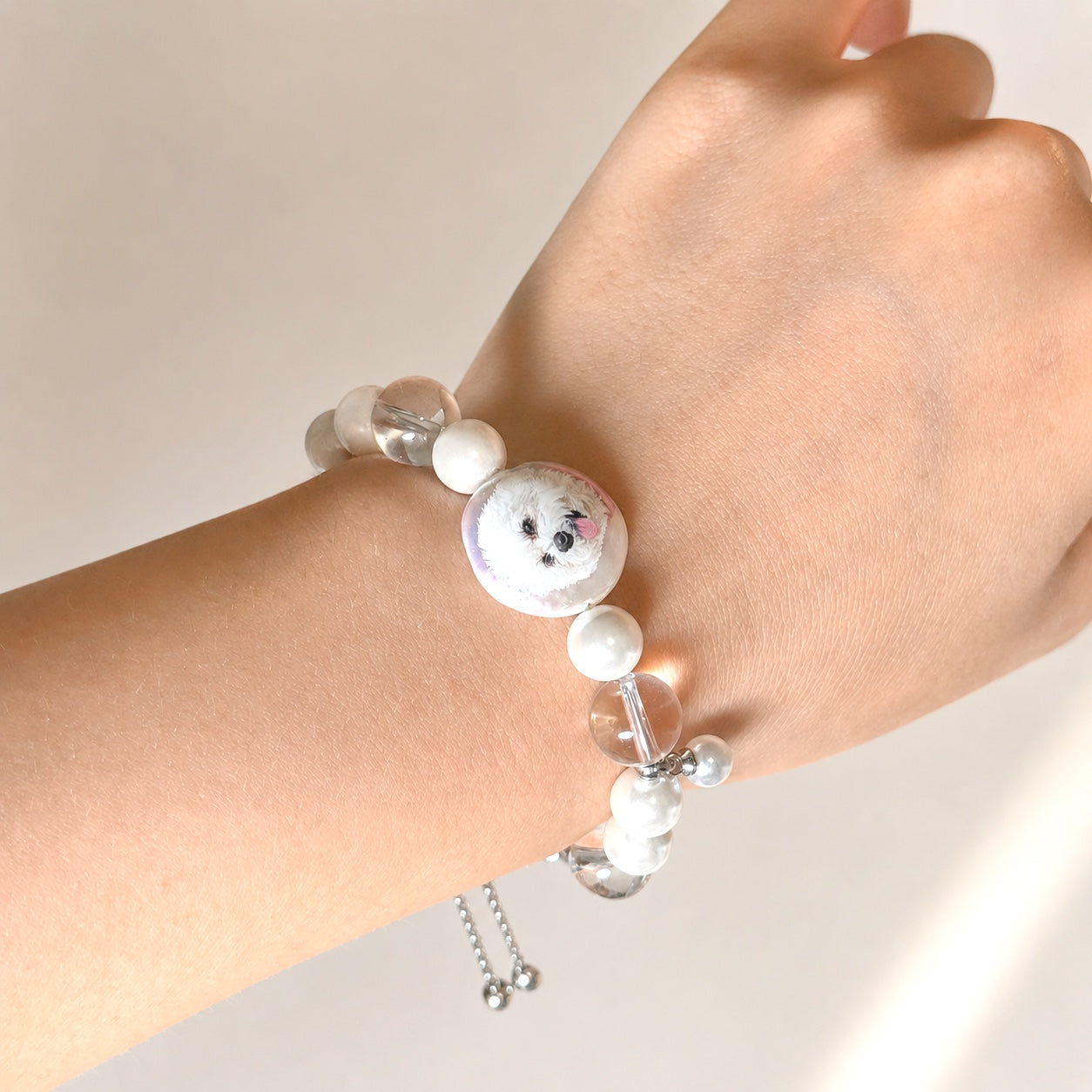Custom pet face bracelet worn on a wrist with pearls, crystals, and a single pet portrait charm visible.